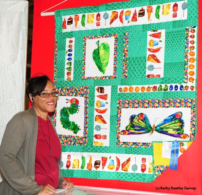 Iris Mayhew of Vallejo, an assistant at McCormack Hall, Solano County Fair, with "The Hungry Caterpillar" quilt by Trudy Molina of Fairfield. (Photo by Kathy Keatley Garvey