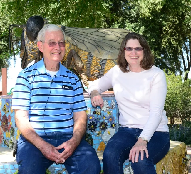 Norm Gary, emeritus professor of entomology at UC Davis who recently retired as a professional bee wrangler, talks bees with Barbara Allen-Diaz, UC ANR vice president. The bee sculpture, in the Häagen-Dazs Honey Bee Haven on Bee Biology Road, UC Davis, is the work of Donna Billick. (Photo by Kathy Keatley Garvey)