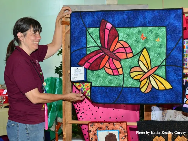 McCormack Hall superintendent Gloria Gonzalez hangs "Butterfly Lovers" by Tina Waycie of Vallejo. (Photo by Kathy Keatley Garvey)