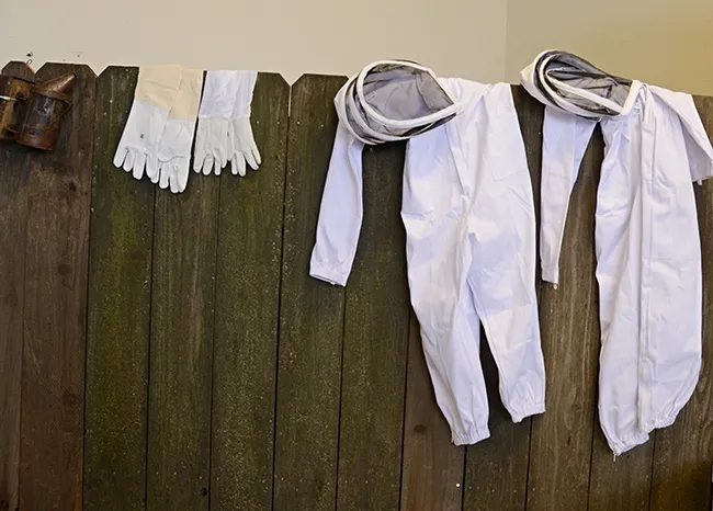 Protective equipment--bee suits, gloves and smokers--lined a fence in Madden Hall. (Photo by Kathy Keatley Garvey)