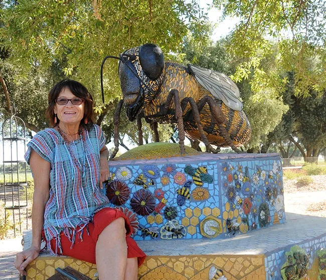 This is "Miss Bee Haven," a worker bee ceramic-mosaic sculpture that anchors the Häagen-Dazs Honey Bee Haven. It is the work of Donna Billick (shown) of Davis, a self-described "rock artist." (Photo by Kathy Keatley Garvey)