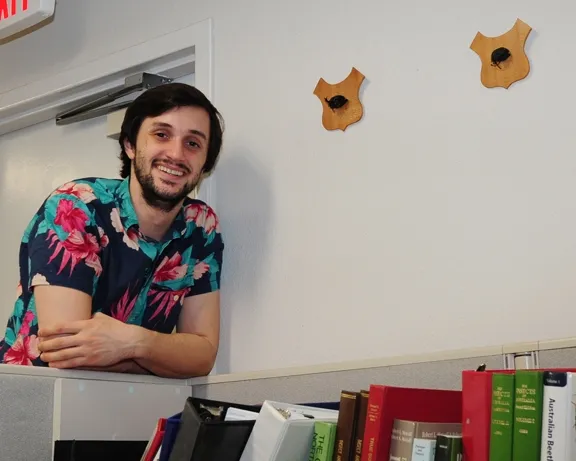 Wade Spencer, a UC Davis entomology major who works at the Bohart Museum of Entomology, stands next to the mounted heads of rhino beetles. (Photo by Kathy Keatley Garvey)