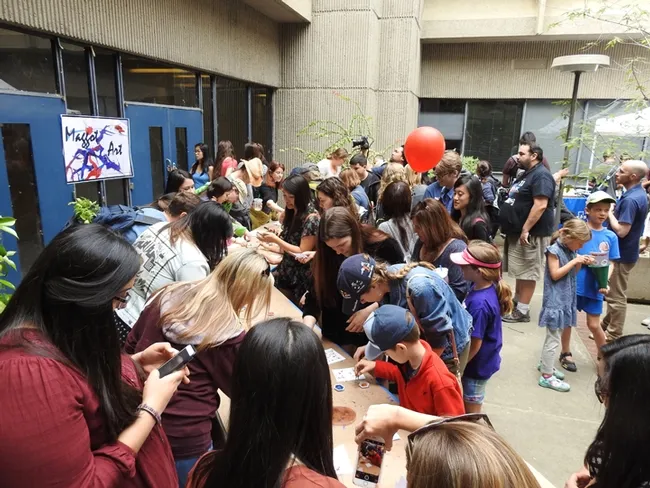 A crowd circulates around the maggot art tables, where participants could dip a maggot into non-toxic, water-based paint, let it crawl around, and create art.