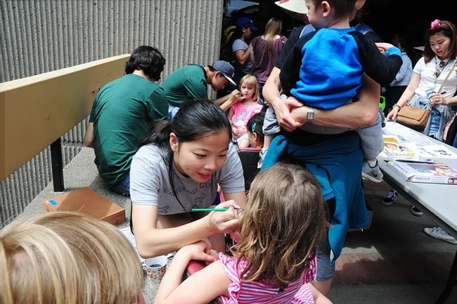 Maia Lundy, president of the UC Davis Entomology Club, creates a face painting. She drew scores of monarch butterflies and caterpillars.