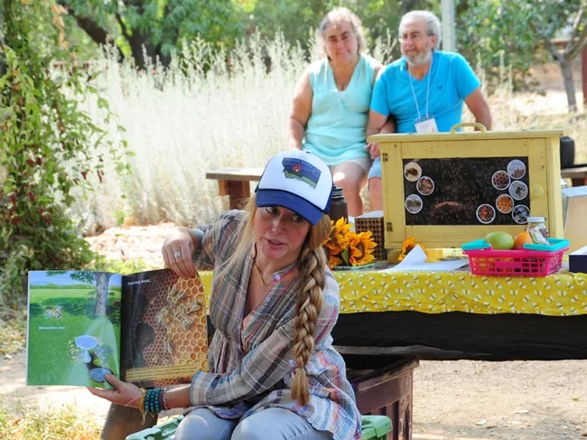 Sarah the Bee Girl reads a book about bees. In back are WAS members Cyndi and Jim Smith of Donney Lake, Wash. Cyndi serves as the secretary. (Photo by Kathy Keatley Garvey)