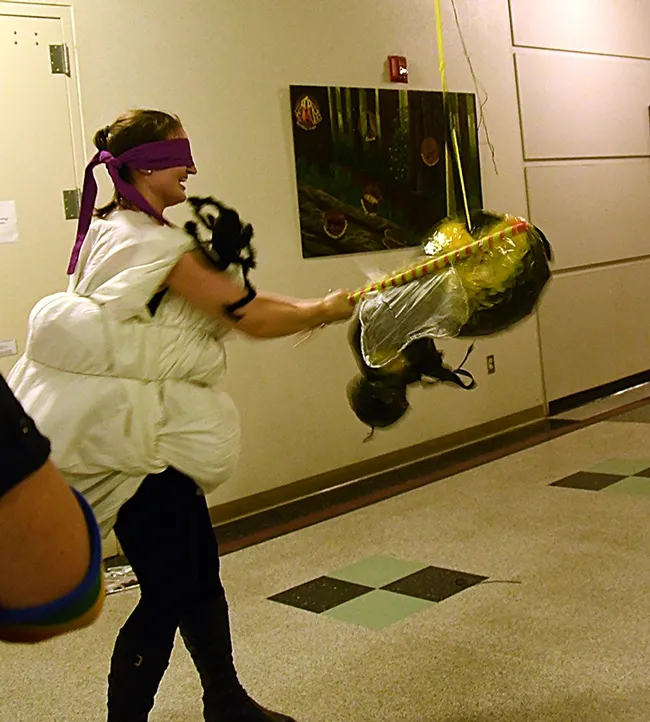 UC Davis PhD student Charlotte Herbert takes a swing at the fly pinata that she and her fiance, George Alberts, created for the Bohart Museum of Entomology Halloween party. (Photo by Kathy Keatley Garvey)