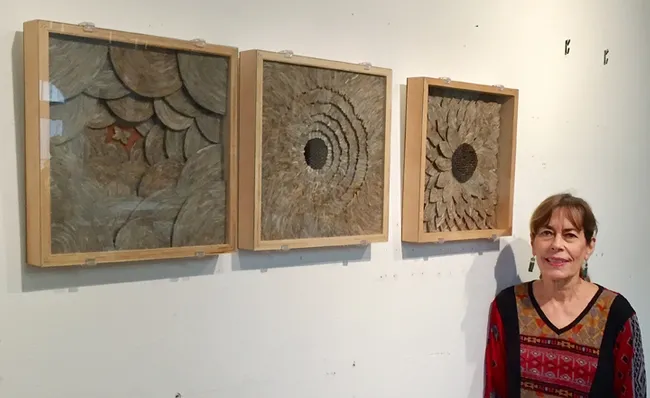 Artist Ann Savageau stands next to her triology of wall pieces made from hornet nest paper. The UC Davis Design Museum show begins Jan. 8 and continues through April 22.