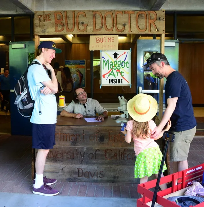Bug Doctor Brendon Boudinot answers a question from Lilliana Phillips, 5, of Carmichael, as her father, William Phillips, watches. (Photo by Kathy Keatley Garvey)