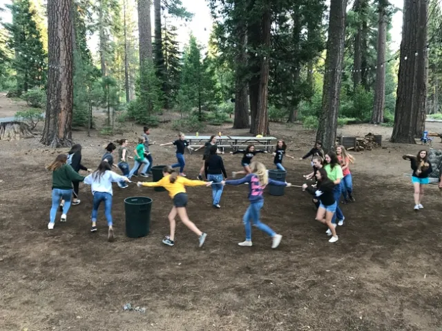 Youth outdoors running in a circle holding hands