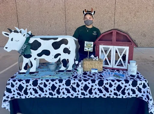 Melina standing behind a table with a cow display on it
