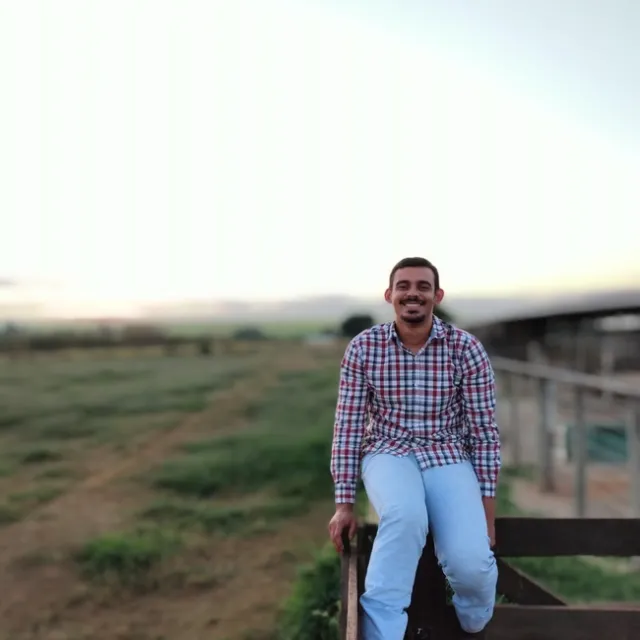 Willi Meireles sitting on a fence smiling