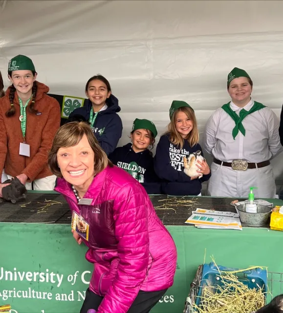 Secretary Ross poses in front of the California 4-H botth with a few 4-H'ers.