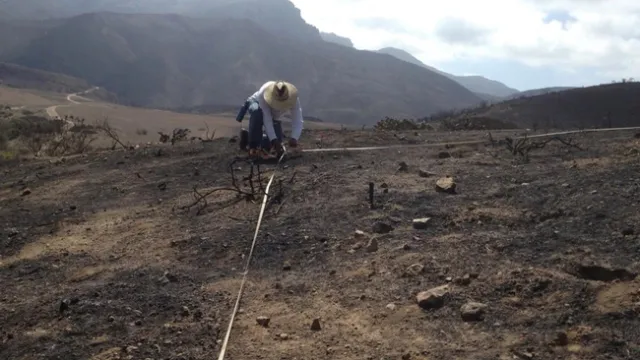Researcher crouches in a field of exposed soil