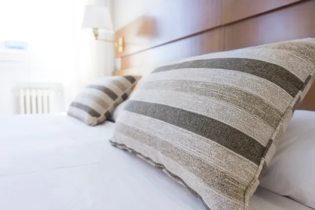 A freshly made bed with white sheets and striped pillows.