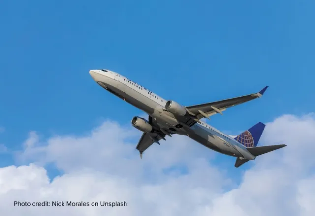 A view of the underside of a United jet against a blue sky.