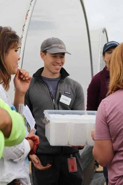 Visitors touring a farm taste blueberries.