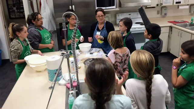 A woman leading kids in a cooking demonstration.