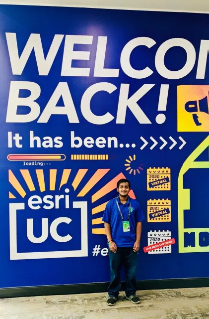 Youth standing in front of blue wall with large lettering and graphics
