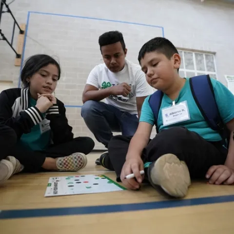 4-H Teen Teacher helping students complete the Hack Your Harvest activity.