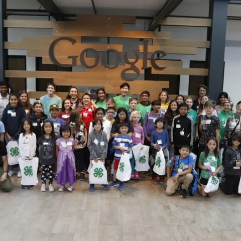 CS Pathway Team, volunteers, Googlers, and youth participants posing in front of a Google sign.