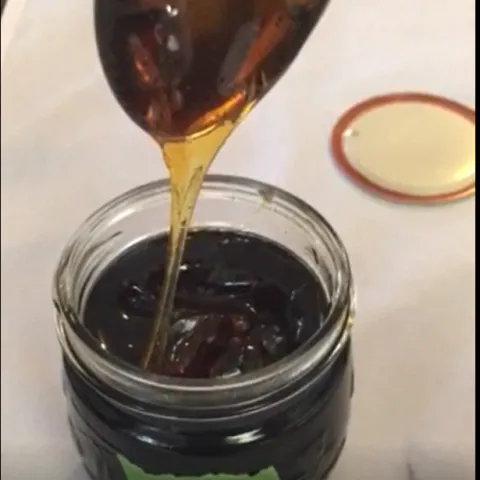Honey drips from a spoon held above a jar.