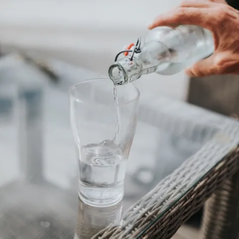 Water pours from a clear bottle into a drinking glass