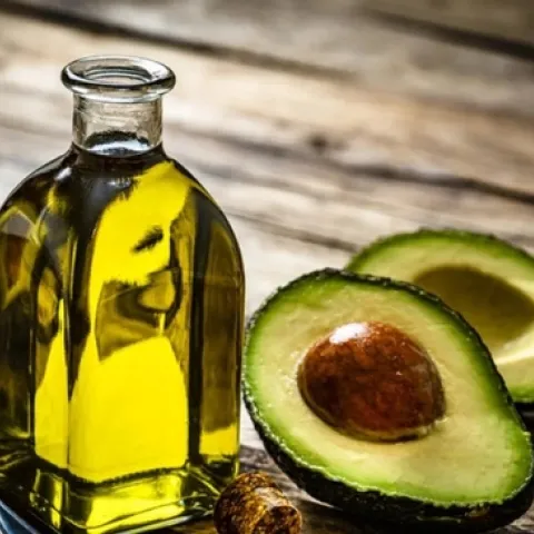 Bottle of avocado oil and an avocado cut open