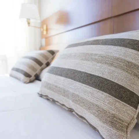 A freshly made bed with white sheets and striped pillows.