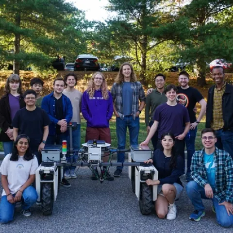 Students pose with their advisor next to the agricultural robot they designed