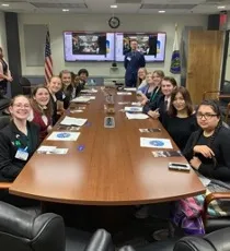long conference table with people seated on both sides facing camera