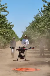 Person controls a drone as two other people look on