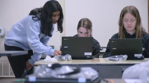 Three young people work on laptops