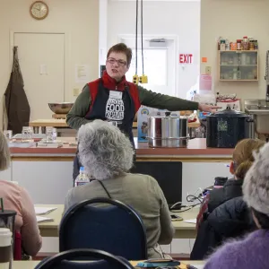Standing woman instructing a group of seated adult students