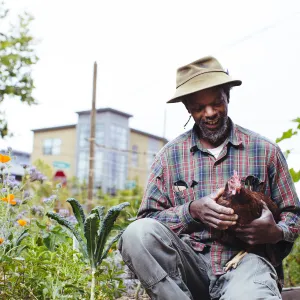 Small farm owner holding chicken in arms